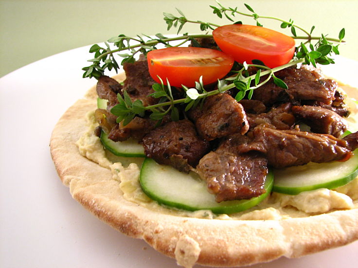 Pita topped with hummus lamb and salad