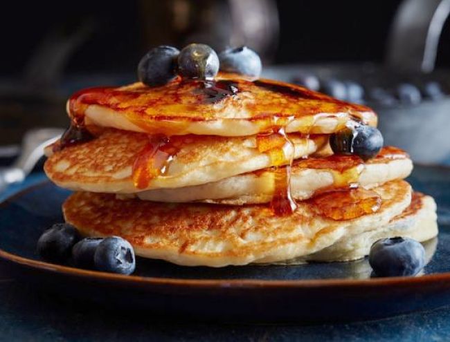 Pancakes with freshly blueberries and drizzled honey