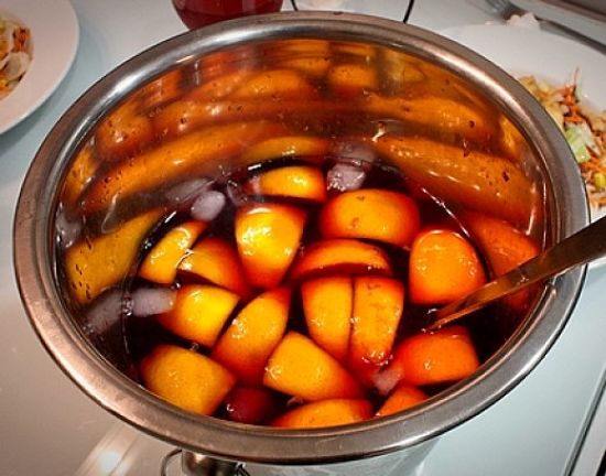 Mixing the sliced fruit with wine and spices to infuse and marinate before serving.