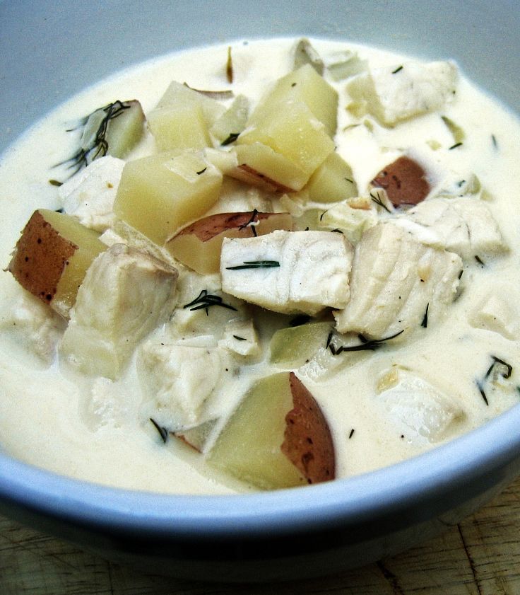 A bowl of fish chowder with white firm fish, red potatoes, chopped dill, herbs and spices