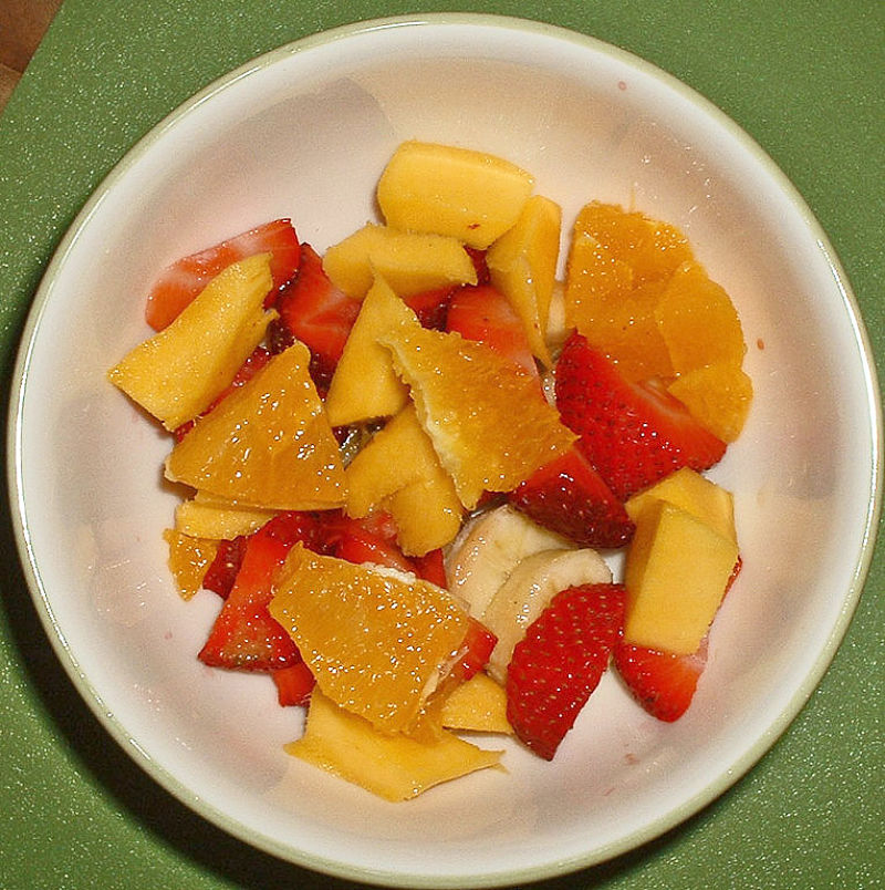 Ambrosia fruit salad is marinated to blend the flavors of a variety of fruits, topped with coconut and whipped cream 