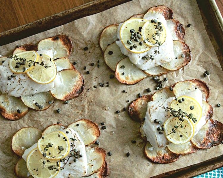 Fish is easily cooked on a sheet pan on a bed of potato slices. Lining the pan with parchment paper helps prevent burning, makes it easy to remove the fish and makes cleaning easier.